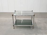 Front view of chrome and brass two-tier side table