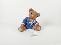 Front view of resin teddy bear coin bank showing attire and seated pose