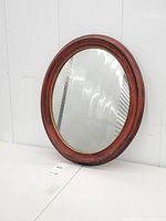 Full view of oval mirror leaning against wall