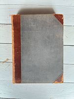Closed book showing front cover with cloth boards and leather corners