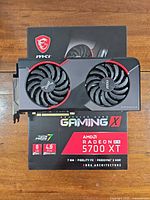 Graphics card resting on its MSI Gaming X box, showing dual fans and overall condition