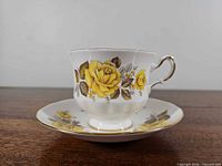 Side view of teacup on saucer showing yellow rose design