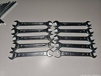 Ten identical chrome open-end wrenches laid out side by side