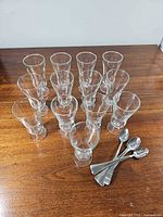 All 12 glasses arranged with 7 spoons on wooden surface