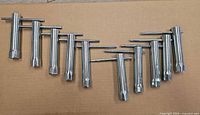 Ten chrome tube wrenches laid out showing full view