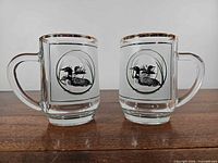 Front view of both Luminarc glass mugs showing loon decals and gold rims