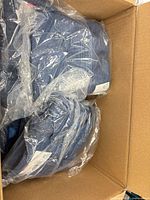Box containing multiple blue shirts in individual plastic bags