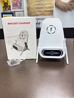 Front view of wireless charger next to box and USB cable