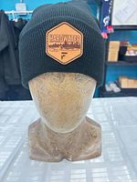 Front view of dark green rib-knit toque on mannequin displaying Hardwater logo patch