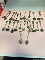 All 23 souvenir spoons laid out on surface