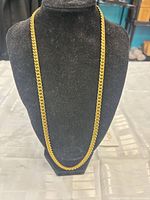 Front view of full length gold-tone curb chain on display bust