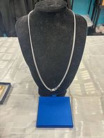 Full view of silver-tone chain on display with box beneath