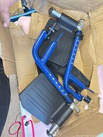 Pair of blue wheelchair footrests with footplates inside damaged box