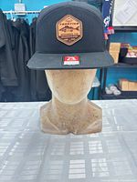 Front view of black Richardson snapback hat with tan leather patch