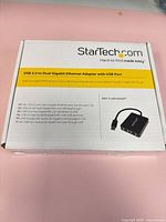 Front of retail box showing product name, features, and image of the adapter