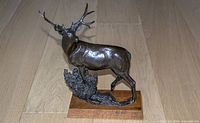 Oblique front view of bronze buck sculpture on wood base