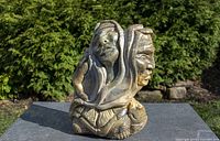 Full view of soapstone sculpture showing faces, hand, turtle and fish on base