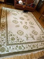 Full view of ivory and green wool rug in room setting
