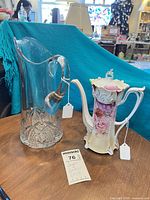 Overall view of clear glass pitcher and floral porcelain teapot on table