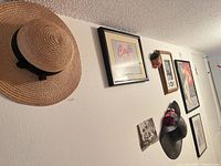 Overview of hats and framed wall art arranged on the hallway wall