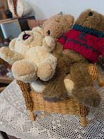 Three teddy bears seated on wicker chair