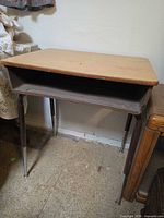 Front view of vintage school desk showing wood laminate top, open cubby, metal legs