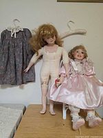 Full lot showing both dolls, dress on hanger, second hanger and white doll chair