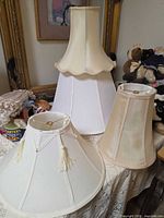 Group shot of three visible lamp shades on table, plus partially visible fourth shade to left