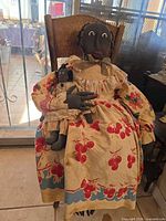 Large cloth doll holding small cloth doll on wooden chair