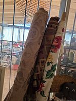 Three upright rolls of patterned upholstery fabric leaning together