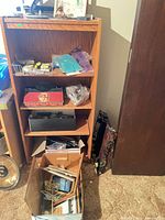 Entire bookshelf with items, clock on floor, box of crafts