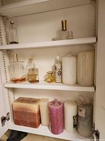 Cabinet shelves showing perfumes and tall pillar candles
