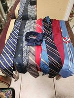 Assorted ties laid out on bench with navy sash on top