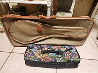Tan instrument-style soft case and floral tapestry bag displayed upright
