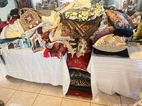 Overall view of piled linens and pillows on two tables