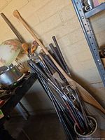 Golf clubs and paddles leaned against wall showing variety