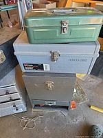 Stack of green, grey and dark grey toolboxes plus silver foam containers