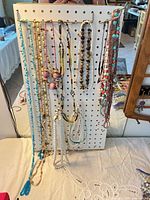 Full view of twelve necklaces hanging on pegboard
