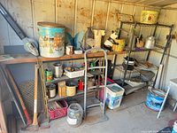 Overall view of left shed area with shelves, ladder, tools, decorative items and supplies visible