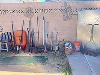 Group view of reel mower, wheelbarrow, spreader, long-handled tools, bucket and planter