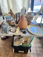 Overall view of table with figurines, vase, platter, gourd and tote below