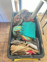 Top view of bin showing pillow, teal mat, striped fabric, assorted textiles