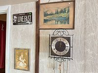 Shows wrought-iron wall clock, landscape print, portrait print, partial novelty sign