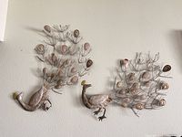 Both metal peacock wall sculptures hanging on wall