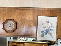 Octagonal pastoral print beside rectangular floral print mounted on wood wall