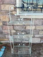 Full view of white metal folding plant stand with three shelves