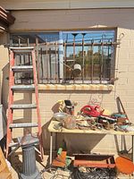 Overall view showing ladder, table with items, pedestal, power tools