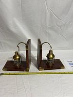 Front view of both wood and brass lantern bookends with tape measure for scale