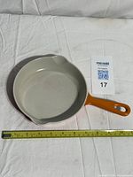 Top view of skillet showing orange handle, light grey interior and measuring tape for scale