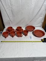 Fiesta Persimmon cups, saucers and bowls laid out with measuring tape